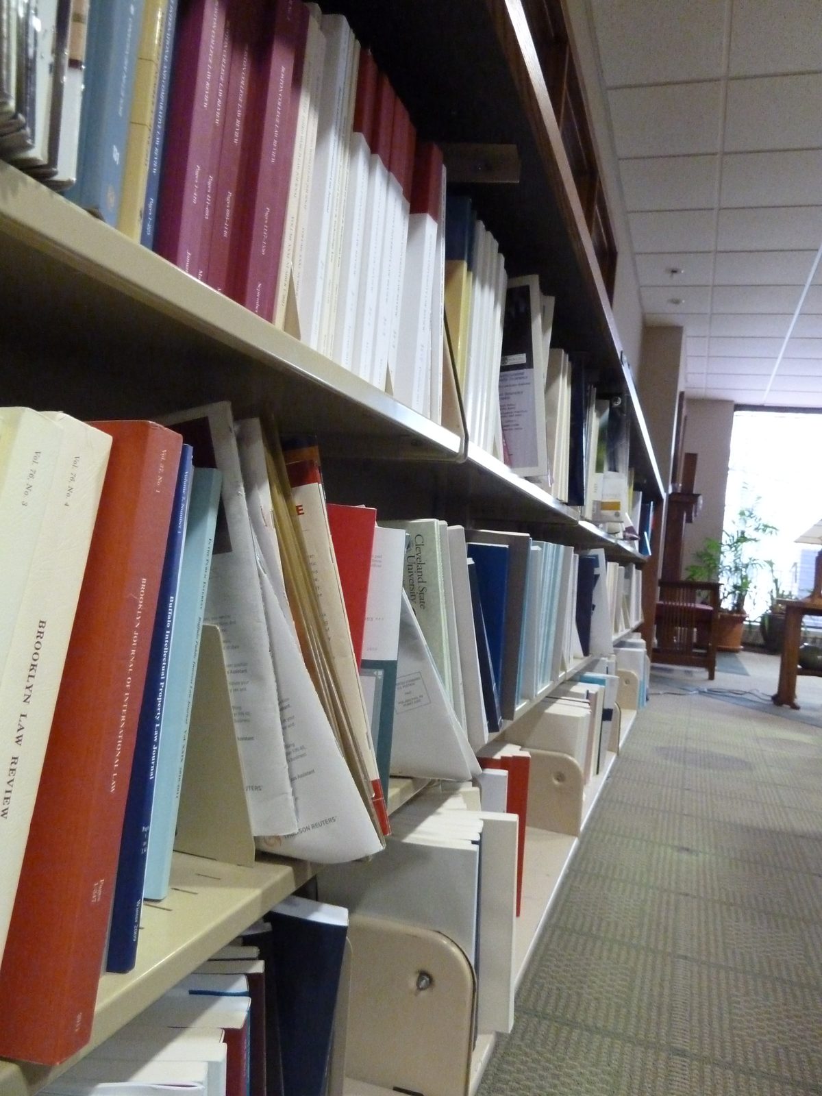 A long run of library shelving filled with bound law journals, seen at an angle down the row.
